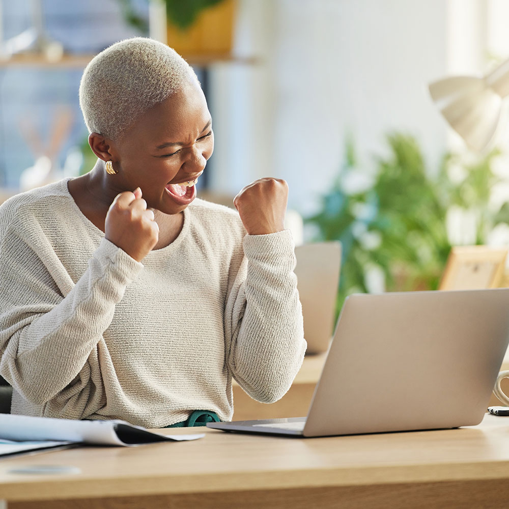 Woman exclaiming in happiness in an office with laptop