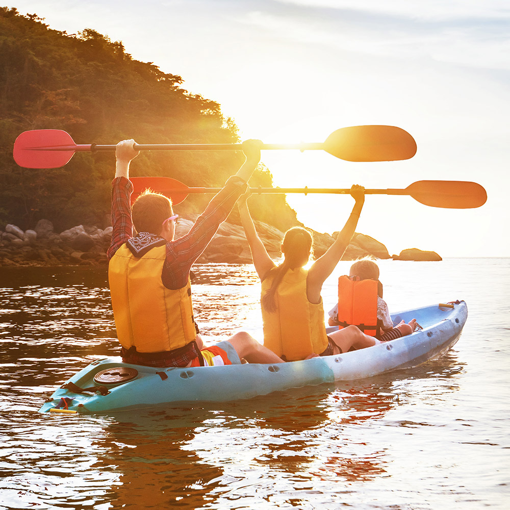 family kayaking at sunset