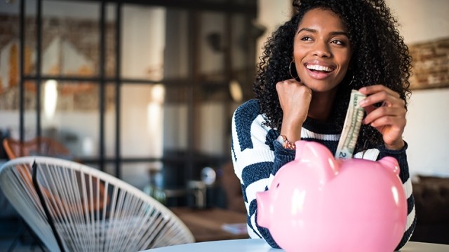 woman putting money in piggy bank