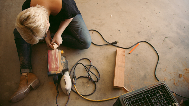 Woman sanding wood on the garage floor