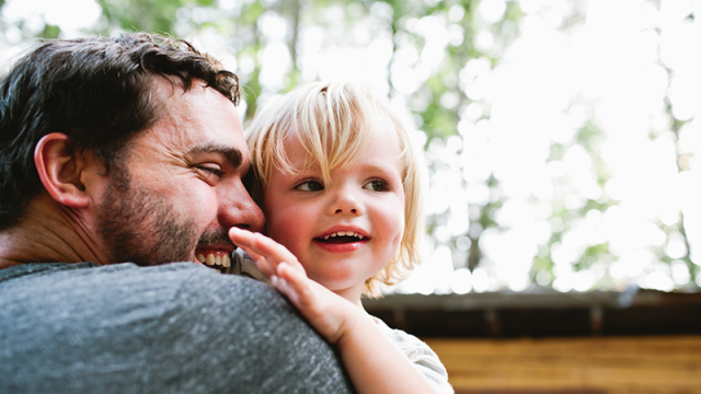 Father hugging a toddler outside their house