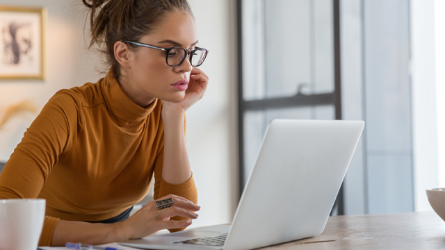 Woman in reviewing statements on laptop