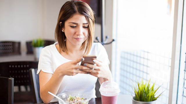Woman using smartphone while having lunch