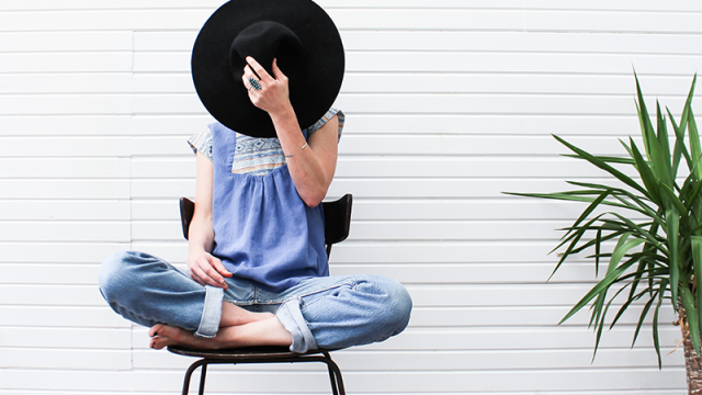 Young woman hiding behind her hat