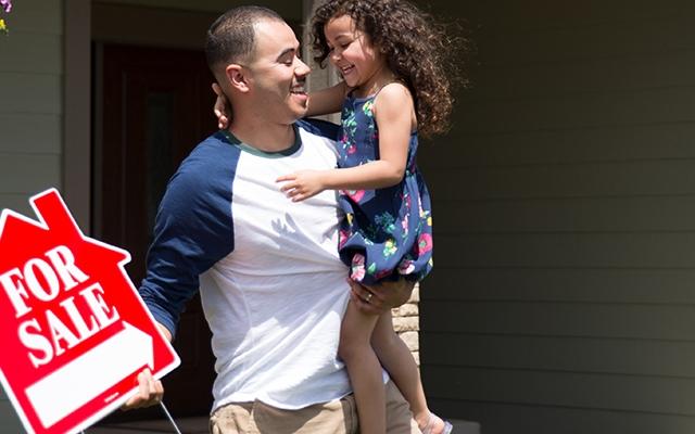 Daughter holding a house for sale sign and his daughter
